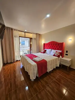 a bedroom with a large bed with a red headboard at Hotel Sumac Samari in Puquio