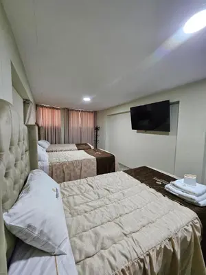 a hotel room with three beds and a flat screen tv at Hotel Sumac Samari in Puquio