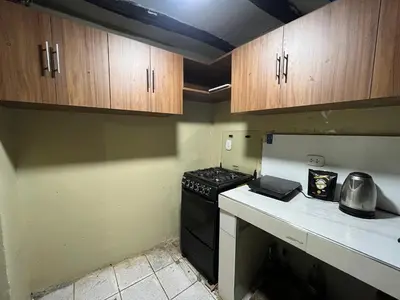 a kitchen with a stove and wooden cabinets at Habitación con recojo desde el aereopuerto in Cusco