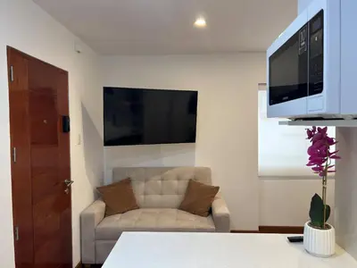 a living room with a chair and a flat screen tv at Av arequipa 603B in Lima