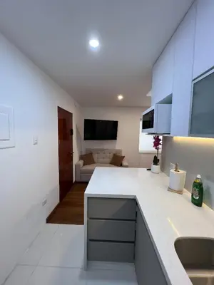 a kitchen with a white counter top and a living room at Av arequipa 603B in Lima