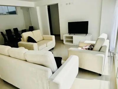 a living room with white furniture and a flat screen tv at Hermoso depa a 10 min del Centro de Huancayo in Huancayo