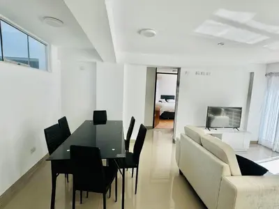 a dining room and living room with a table and a couch at Hermoso depa a 10 min del Centro de Huancayo in Huancayo