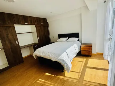 a bedroom with a large bed and a wooden floor at Hermoso depa a 10 min del Centro de Huancayo in Huancayo