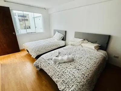 a bedroom with two beds with white sheets and a window at Hermoso depa a 10 min del Centro de Huancayo in Huancayo