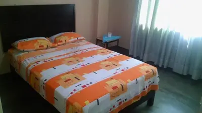 a bedroom with a bed with an orange and white comforter at Francisco D Francisco in Lima
