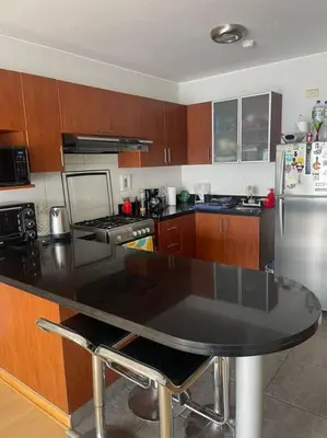 a kitchen with a black counter top and a refrigerator at Departamento en Miraflores, Lima in Lima