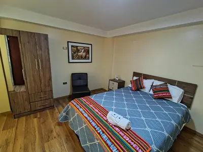 a bedroom with a bed with a blue comforter at Departamento en La casa de Teresita in Cusco