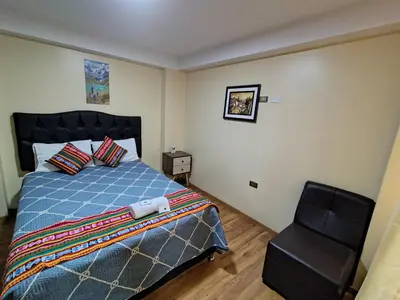 a bedroom with a bed and a chair at Departamento en La casa de Teresita in Cusco