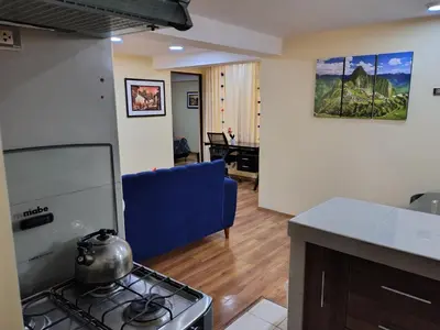 a kitchen and living room with a stove and a blue couch at Departamento en La casa de Teresita in Cusco