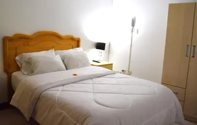 a bedroom with a large bed with white sheets and pillows at Hotel Orlak in Huancayo