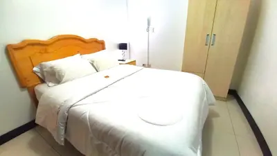 a bedroom with a white bed with a wooden headboard at Hotel Orlak in Huancayo