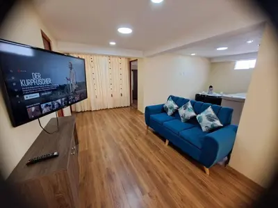 a living room with a blue couch and a flat screen tv at Departamento INTI - casa de Teresita in Cusco