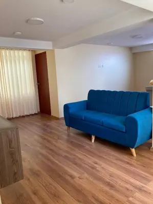 a blue couch in a living room with wooden floors at Departamento INTI - casa de Teresita in Cusco
