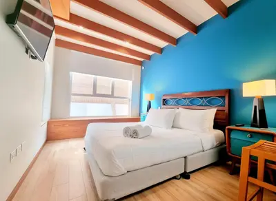a bedroom with a large white bed and a blue wall at E SuiteTOP Tudela San Isidro Lima 2B 202 in Lima