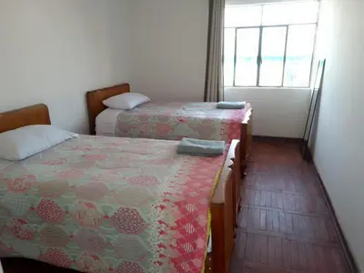 a bedroom with two beds and a window at Kasa-4 B&B Family Home in Huancayo
