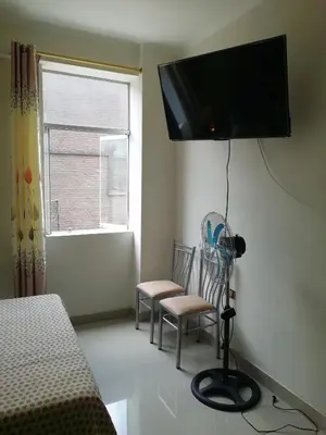 a bedroom with a bed and two chairs and a flat screen tv at ESTUDIO COMPLETO en el CENTRO HISTORICO de LIMA in Lima