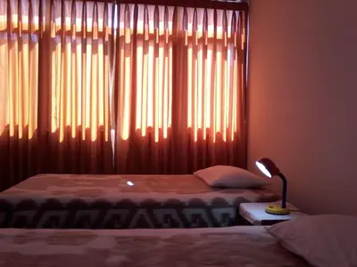 a bedroom with two beds and a window with curtains at Royal Sweet Dreams Airport B&B in Lima