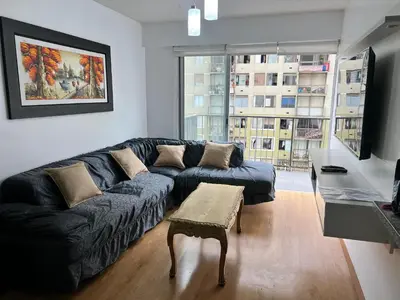 a living room with a black couch and a table at Departamento de 04 dormitorios in Lima