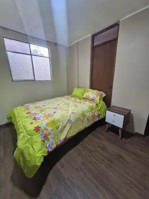 a bedroom with a bed with a green comforter and a window at Apartamento-Santa Anita, Villa Caly in Lima