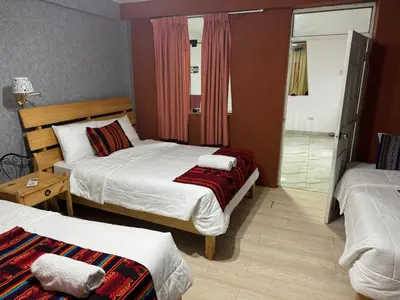 a hotel room with two beds and a bathroom at Hotel Plateros in Cusco