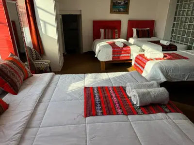 a room with three beds with red and white at Hotel Plateros in Cusco