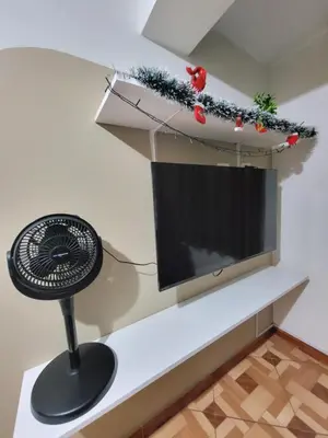 a living room with a fan and a television at Departamento, LUJO HOGAR cerca a PLAZA NORTE - UNI AEROPUERTO in Lima