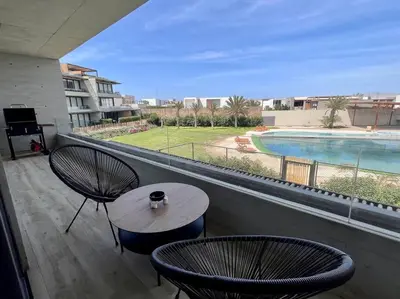 a balcony with a table and two chairs and a pool at Aldea 2BR Boho Style for 4 with Gym, Pool and Cowork in Paracas