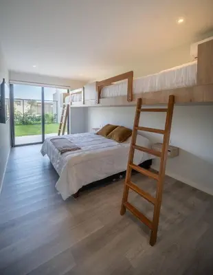 a bedroom with two bunk beds and a chair at Aldea 2BR Family, Big FrontYard for 6 with Gym and Pool in Paracas
