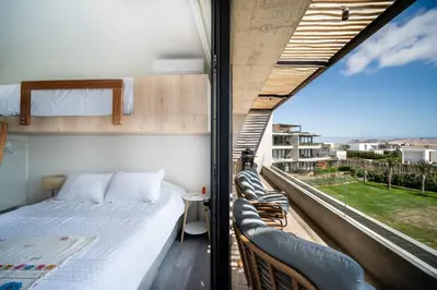 a bedroom with a bed and two chairs on a balcony at Aldea 2BR Ocean View and Kamado BBQ for 6 in Paracas