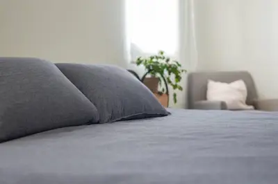 a bed with a gray pillow and a chair at Aldea 2 Bedroom with Private Sauna for 4 in Paracas