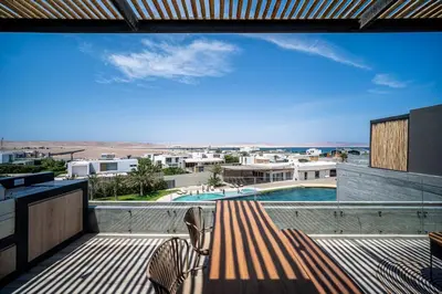 a balcony with a bench and a swimming pool at Aldea 1BR Romance Seascape for 2 in Paracas