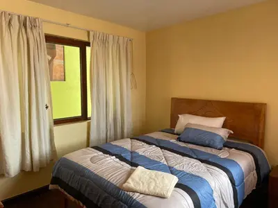 a bedroom with a large bed with a window at Departamentos Belén in Cusco