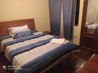 a bedroom with a bed with blue and white sheets at Departamentos Belén in Cusco