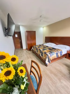 a hotel room with a bed and a table with flowers at Hotel Esencia Suites in Lima