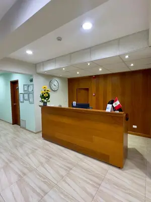 a lobby with a reception desk with a clock on the wall at Hotel Esencia Suites in Lima