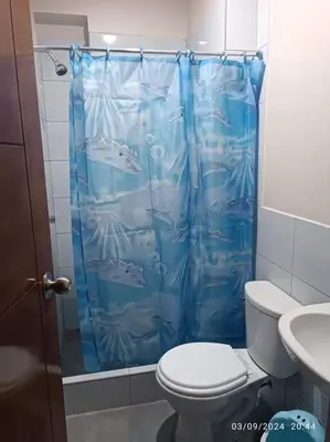 a blue shower curtain in a bathroom with a toilet at MarsHouse in Chirimoyo