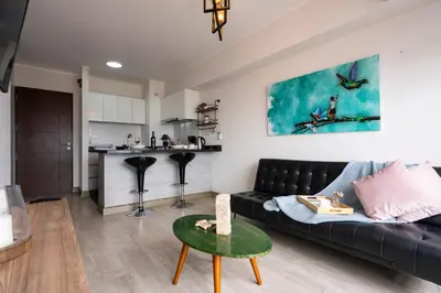 a living room with a black couch and a kitchen at Connect Apartment by Vibrant in Lima