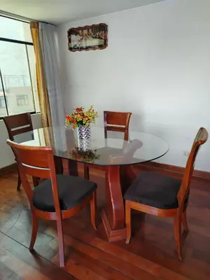 a dining room table and chairs with a vase of flowers at Apartamento acogedor en La Perla in Lima