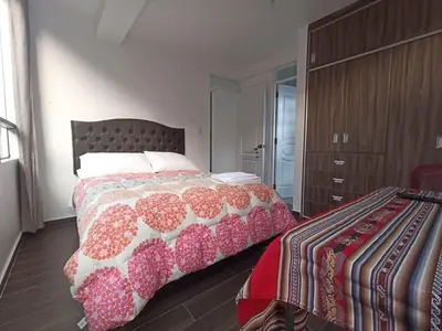 a bedroom with a bed with a red and white blanket at Casa Mónaco in Cusco
