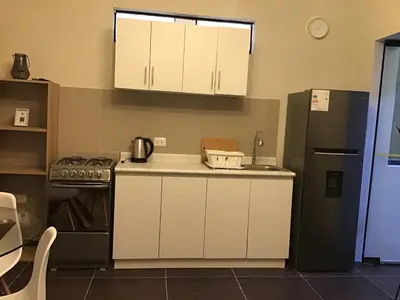 a kitchen with white cabinets and a black refrigerator at Hernandez suites Suite203 in Lima