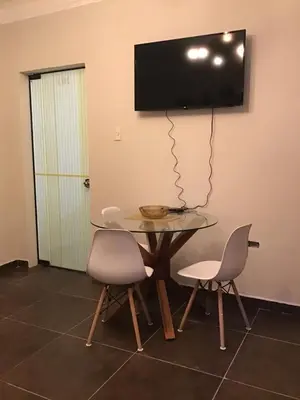 a table with two chairs and a television on a wall at Hernandez suites Suite203 in Lima