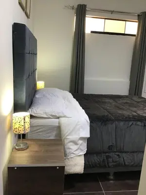 a bedroom with a bed and a table with a lamp at Hernandez suites Suite203 in Lima