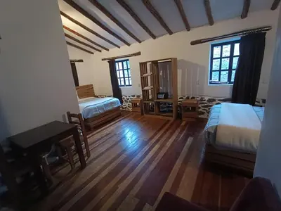 a bedroom with two beds and a desk and a table at Tika bungalows hotel in Ollantaytambo