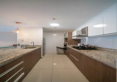 a large kitchen with wooden cabinets and marble counter tops at Luxury Flat Miraflores Pool Gym Fast WiFi Balcony in Lima