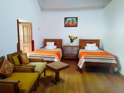 a room with two beds and a chair and a couch at Casa San Pedro Cusco in Cusco
