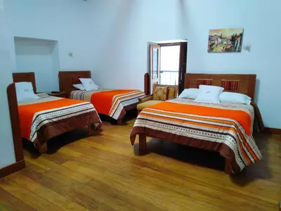 a room with two beds with orange sheets at Casa San Pedro Cusco in Cusco