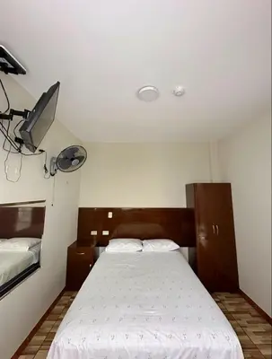 a bedroom with a bed and a tv on the wall at Hostal El Rey in Lima