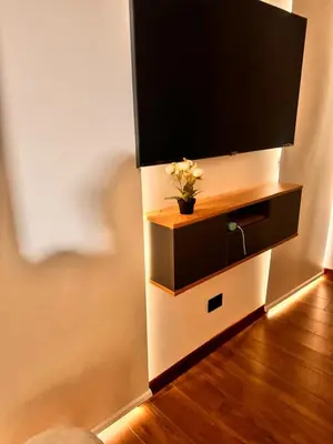 a television on a wall with a vase with flowers at betoben in Lima