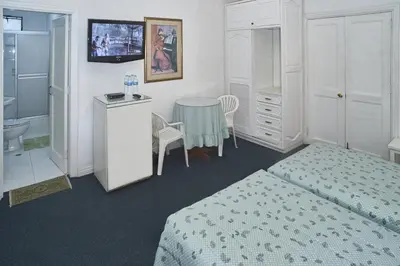 a bedroom with a bed and a table and a bathroom at B&B El Olivar in Lima